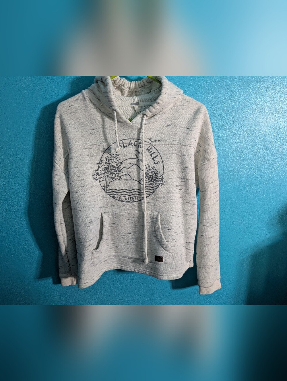 White and gray speckled pullover hoodie with a Black Hills, South Dakota graphic